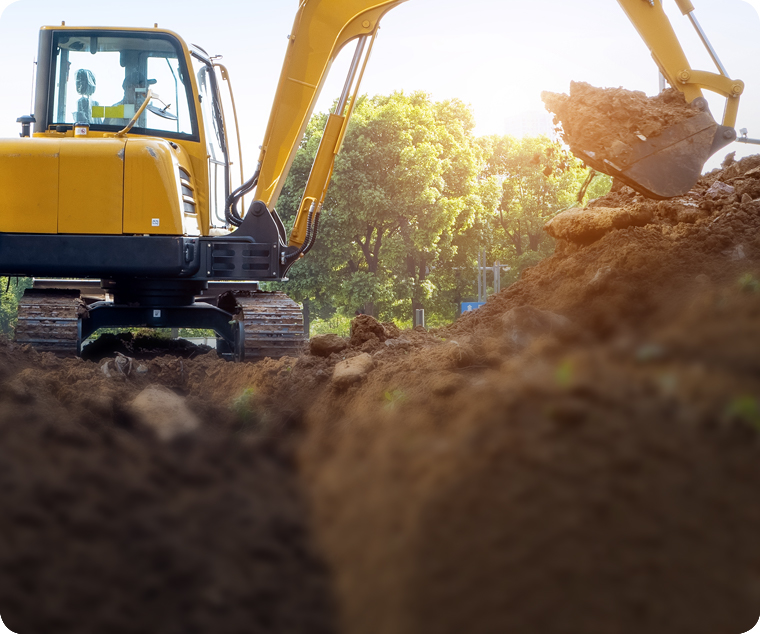 En gul grävmaskin gräver i marken och lägger massorna i en hög